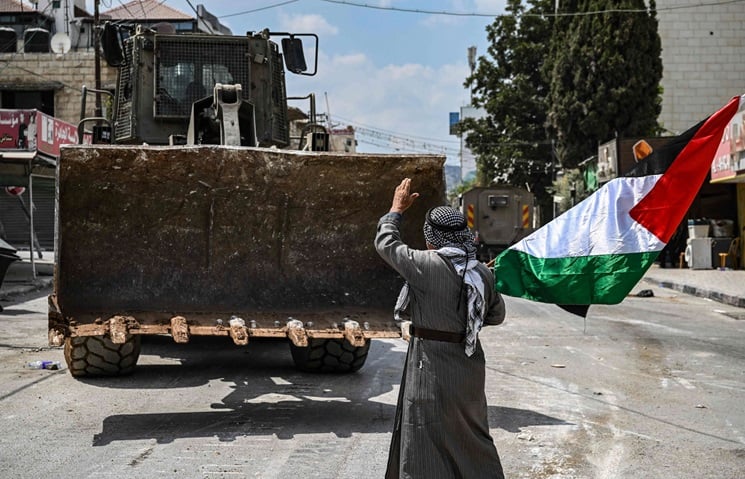 “رسائل من جنين”.. ناشط مسنّ يرفع العلم الفلسطيني ويتمشى بين آليات وجرافات جيش الاحتلال.. من هو؟- (صور)